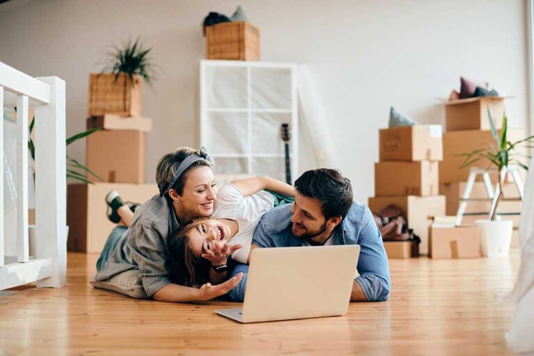 Family labels boxes beside packed furniture while preparing for a residential move.